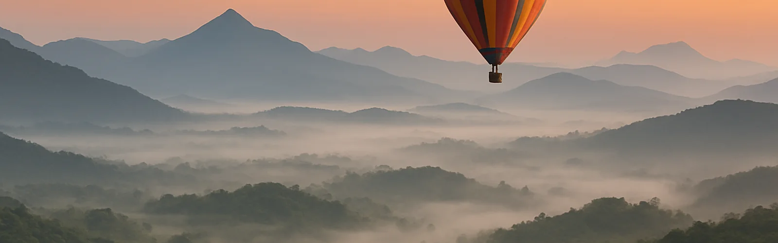A hot air balloon rises above misty hills and green valleys.